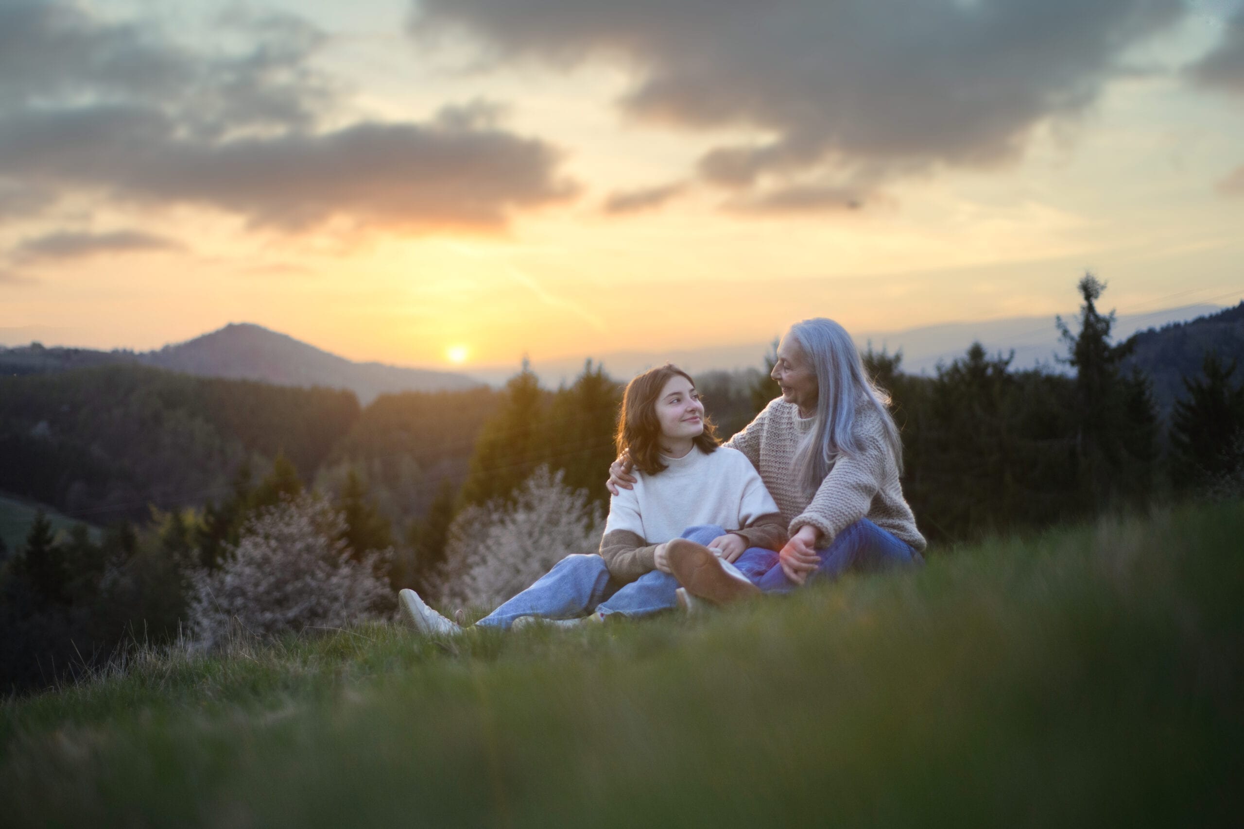 Seniorin und Enkel bei Sonnenuntergang auf Wiese im Harz