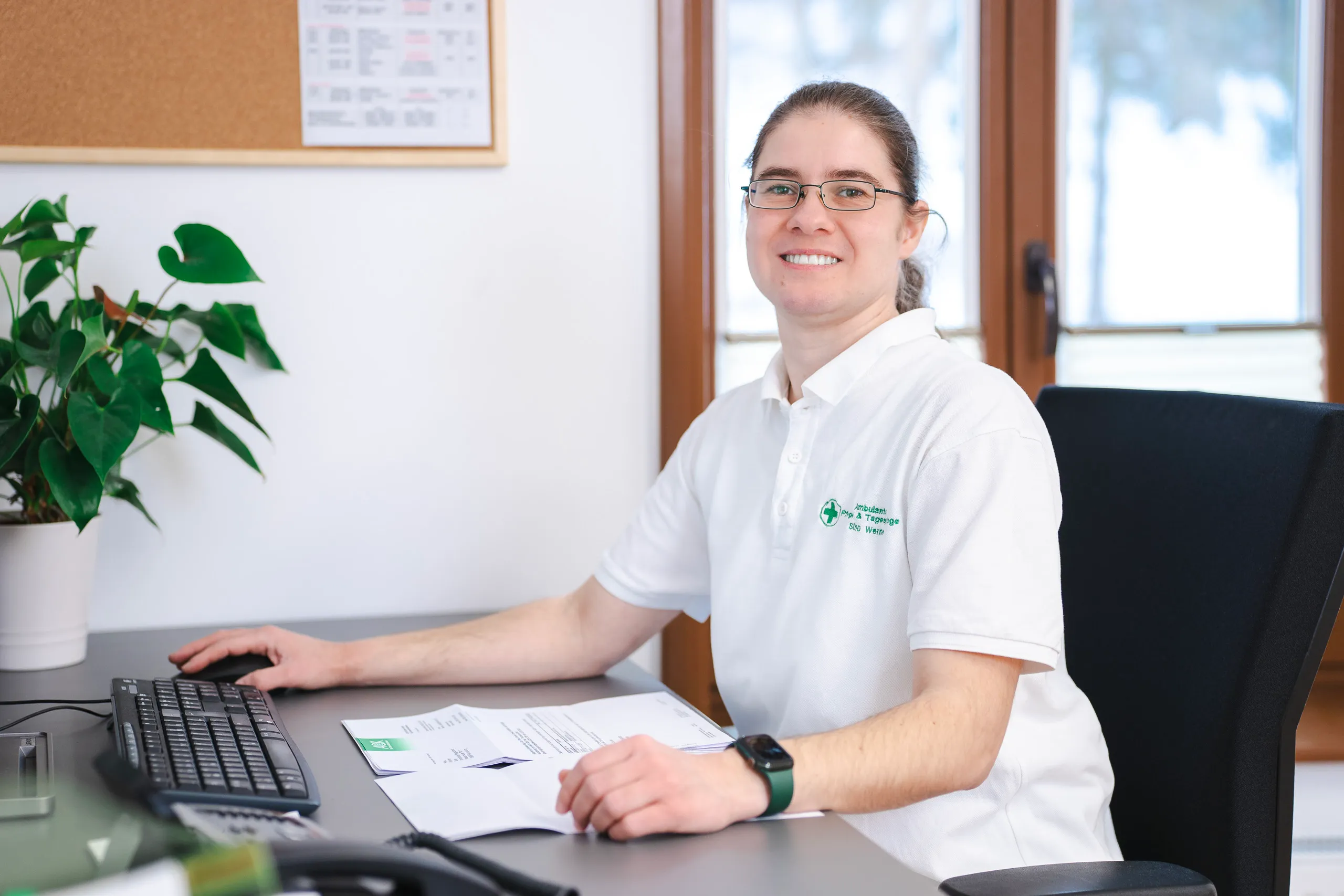 Person am Schreibtisch lächelnd im Büro