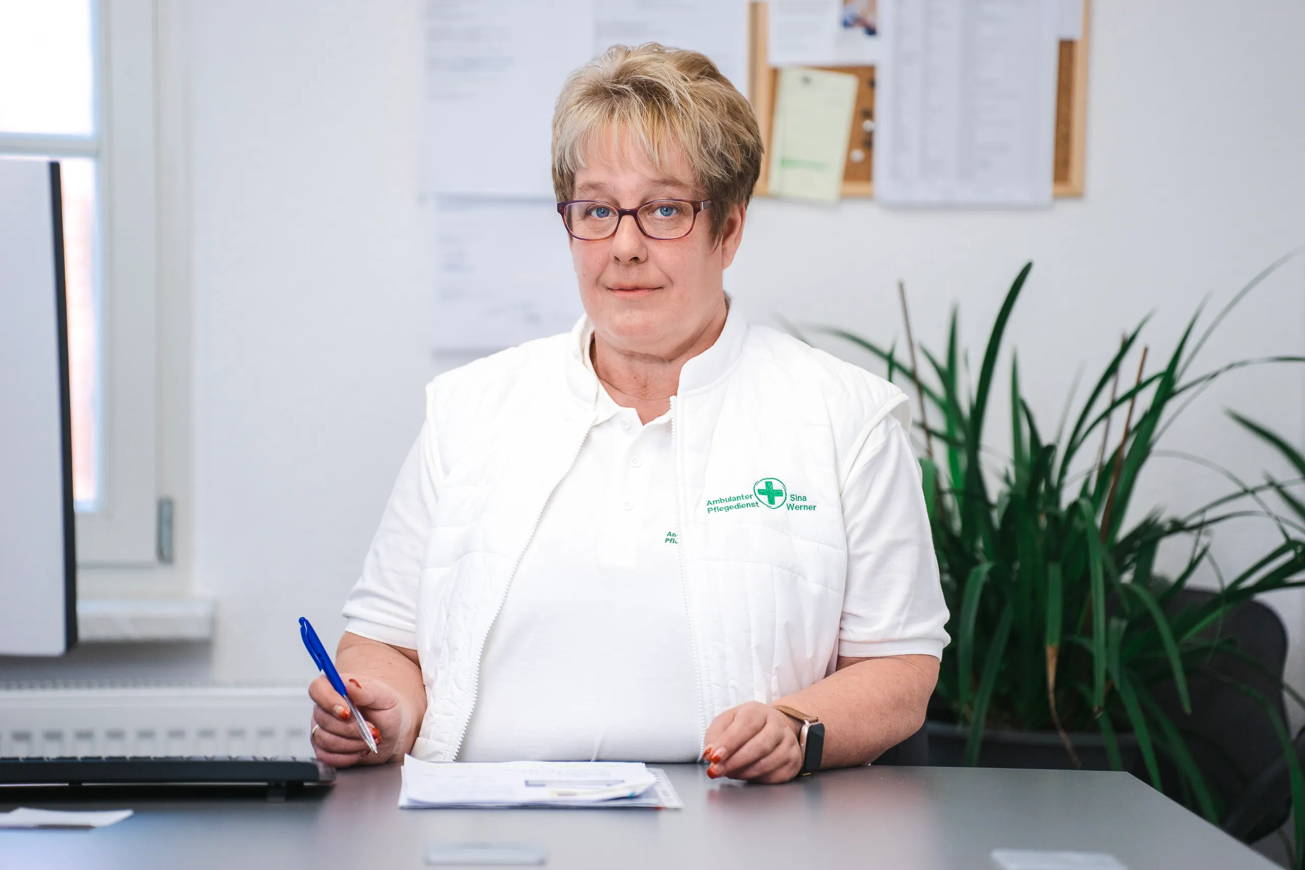 Lächelnde Frau arbeitend am Schreibtisch im Büro.